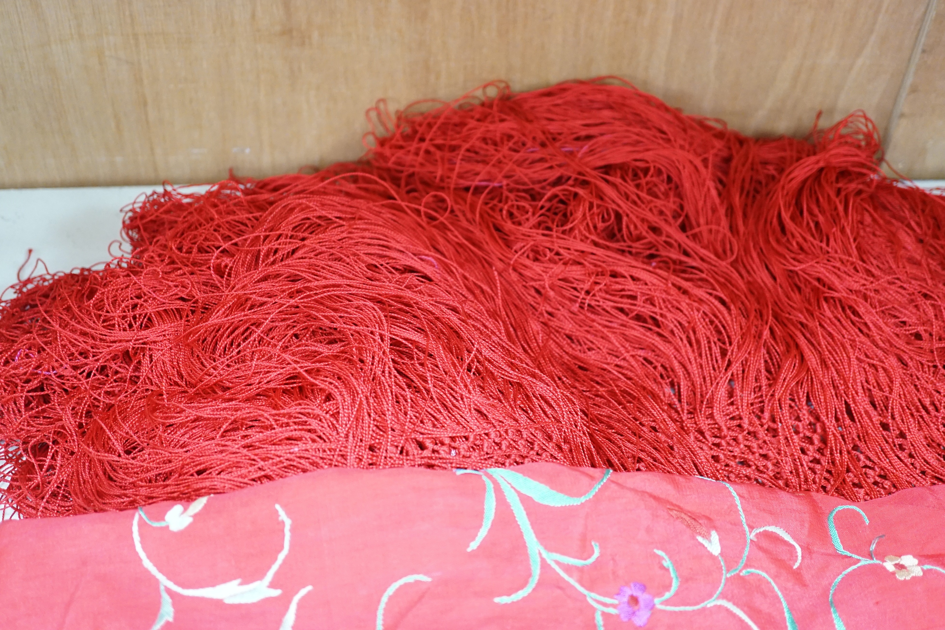 An early 20th century Chinese red silk fringed shawl, with multicoloured polychrome embroidery, 130cms square not including fringe